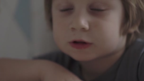 Un niño pequeño come comida en la mesa — Vídeos de Stock