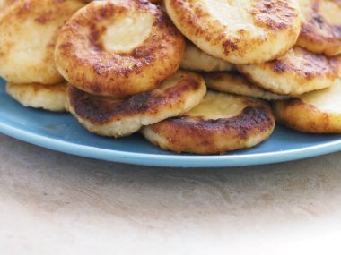 Altın kabuklu lezzetli peynirli kekler bir tabakta yığılır.