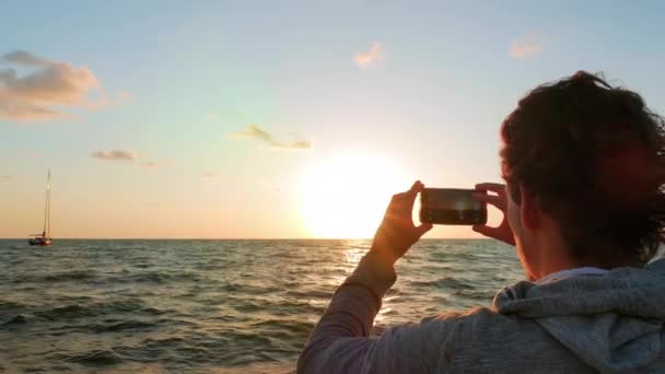 Ung vuxen tar tre bilder av solen faller över horisonten — Stockvideo