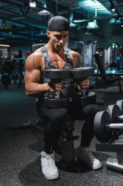 Spor giyim sektöründe formda genç bir adam spor salonunda bir halteri kaldırmaya odaklanmıştı..