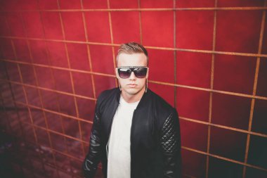 Sokakta elinde sis bombasıyla duran deri ceketli bir adam. Kırmızı duman bombası taşıyan Avrupalı gencin renkli portresi