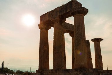 Corinth 'teki tapınağın eski kalıntıları, güneşin ışıkları içinden geçiyor. Yunanistan - arkeoloji geçmişi.