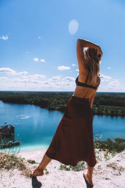 Rummu taş ocağının pitoresk bir noktasında, sarışın bir kadın çıplak ayakla ayakta duruyor, yüksek, kumral renkli bir elbise giyiyor, ve kameraya arkasını dönüyor. Temiz Su