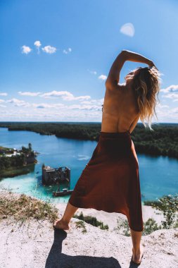 Rummu taş ocağının pitoresk bir noktasında, sarışın bir kadın çıplak ayakla ayakta duruyor, yüksek, kumral renkli bir elbise giyiyor, ve kameraya arkasını dönüyor. Temiz Su