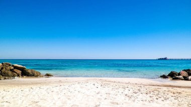 Vada sahilindeki taşlar, şeffaf, turkuaz su ve beyaz kum. Seyahat ve doğa kavramı.