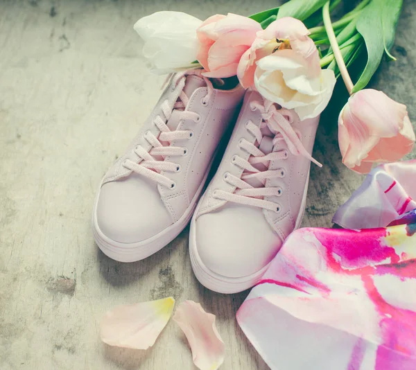 木制背景上的粉红运动鞋和郁金香花 — 图库照片