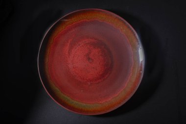 A dark red ceramic plate with a brown vintage pattern