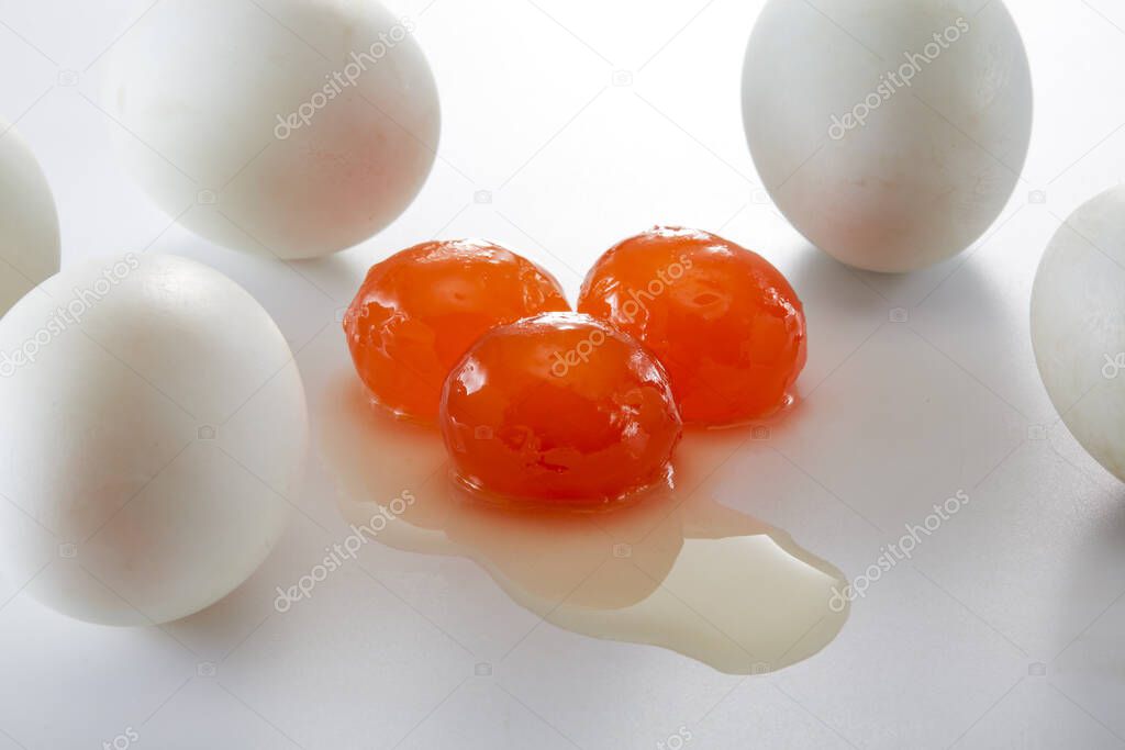 Three salted duck yolks and a pile of salted duck eggs