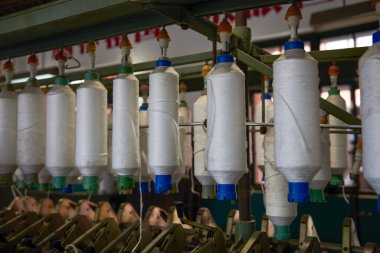 A row of bobbins on a cotton spinning machine clipart