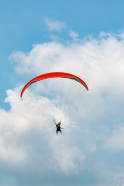 Mavi gökyüzünde uçan insanlı paraglider
