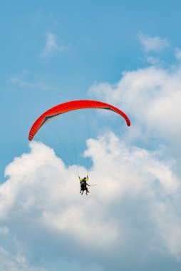 Mavi gökyüzünde uçan insanlı paraglider