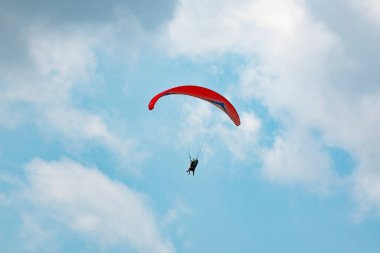 Mavi gökyüzünde uçan insanlı paraglider
