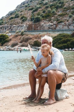 Büyükbaba ve çocuk sahilde oynuyorlar.