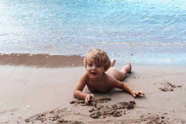 Kumsaldaki küçük şirin çocuk.
