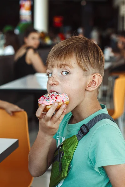Мальчик Ест Разноцветный Пончик — стоковое фото