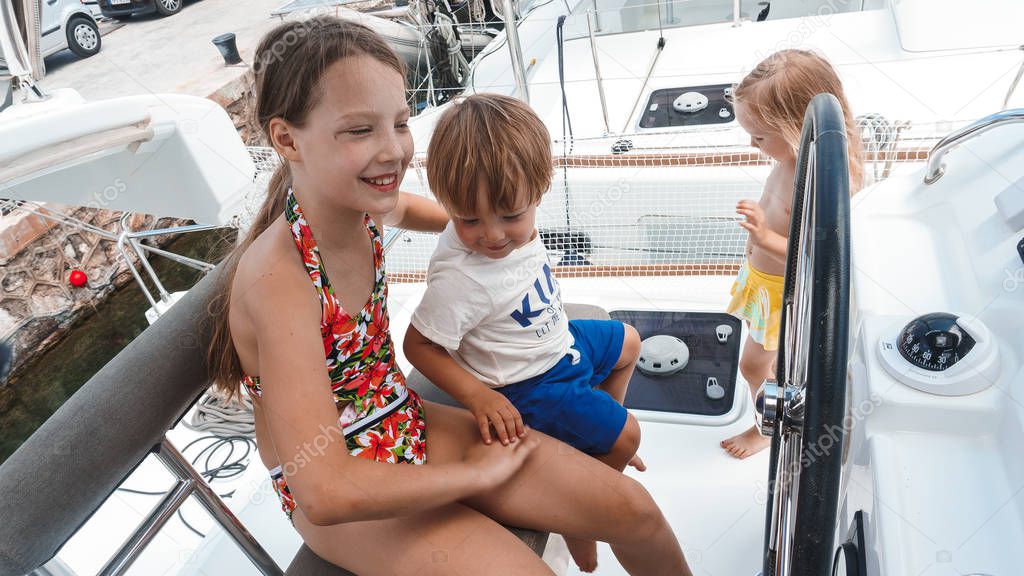 Two sisters and brother rejoicing on yacht in summer day