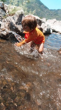 Suda oynayan genç çocuk.