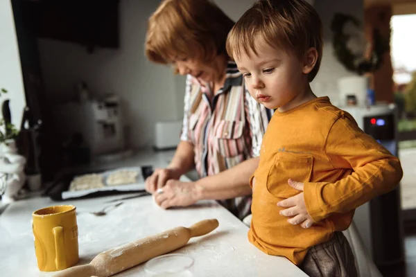 granny and grandson cooking pies in the kitchen