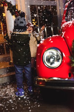 Arka planda arabası olan çocukların portresi.