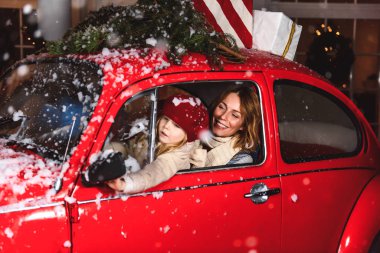 Noel zamanı. Anne ve kızı karda kırmızı bir arabada gülüyorlar.