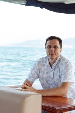 Sandalyede oturan ve kameraya bakan yakışıklı bir adamın portresi.