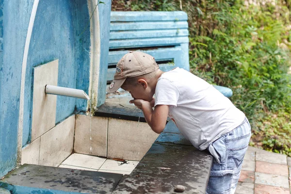 可爱的小男孩在室外饮水机里喝水 — 图库照片