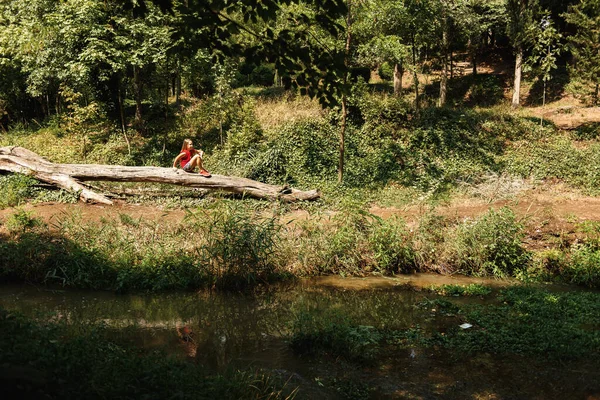 Ormandaki Gölün Kıyısındaki Kütükte Oturan Tatlı Küçük Kız — Stok fotoğraf