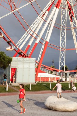 Dönme dolabın yanında yürüyen insanlar.