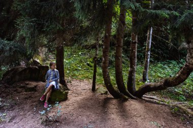 Yeşil bir ormanda yürüyen genç bir kız.