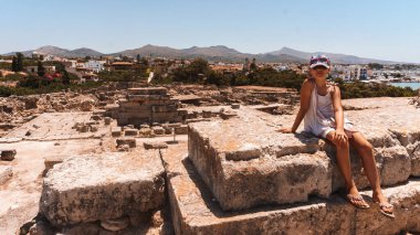 Genç kız antik şehrin kalıntılarında oturuyor. 