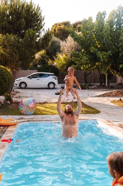 Mutlu aile havuzda eğleniyor.