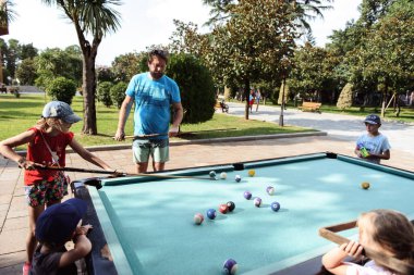 Parkta bilardo oynayan çocuklu baba.