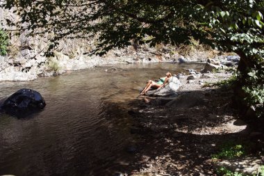 Nehrin arka planında mayo giymiş genç bir kadın.