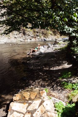 Nehrin arka planında mayo giymiş genç bir kadın.