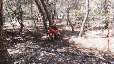 Baba ve küçük oğlu parktaki çitlerden bakıyor.