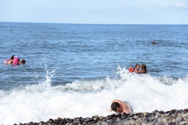 Çocuklu insanlar denizde yüzüyor.