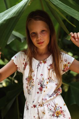 Bir ağacın yaprağının altında duran kız