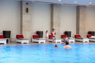 Çocuklar otel havuzunda yüzüyor.