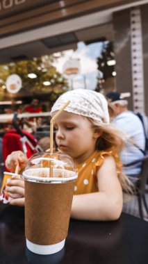 Sarı elbiseli kız kafede milkshake içiyor.