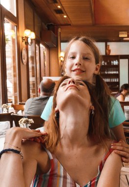 Kafede oturan ve gülümseyen kızları olan kadınlar.