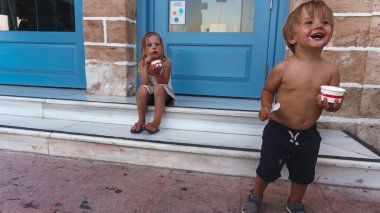 Küçük kız ve çocuk bir dükkan penceresinin yanında oturuyor.