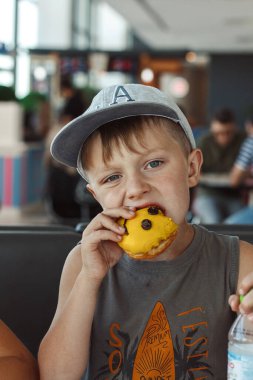 Küçük çocuk renkli bir çörek yiyor.