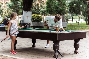 Baba kızıyla bilardo oynuyor.