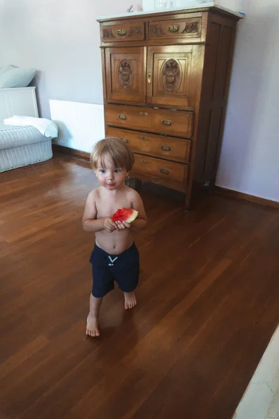 小男孩拿着西瓜在屋里走来走去 — 图库照片