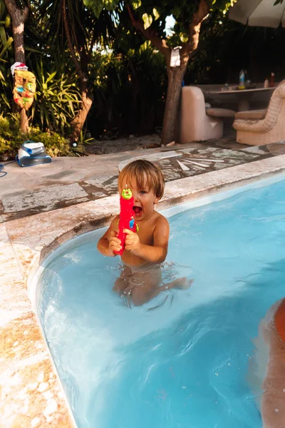 プールで水鉄砲で遊ぶ少年は — ストック写真