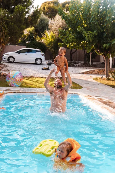 息子と一緒に家の近くのプールで泳いでいるお父さん — ストック写真