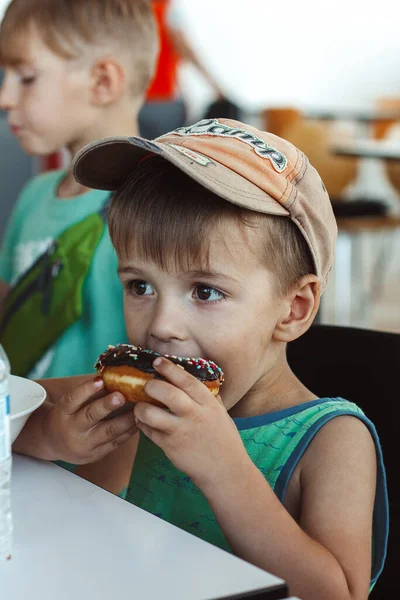 Маленький Мальчик Ест Цветной Пончик — стоковое фото