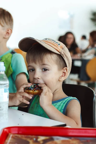 Маленький Мальчик Ест Цветной Пончик — стоковое фото