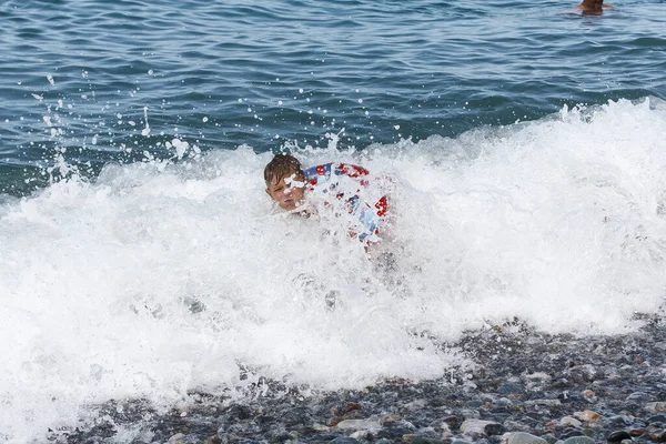 Little boys swimming in the waves of the sea