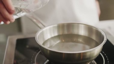 Closeup cook man pours vinegar into water